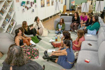 Students chat as they sit in a circle on the carpet and on the couches in CASA Pitzer’s living room space.